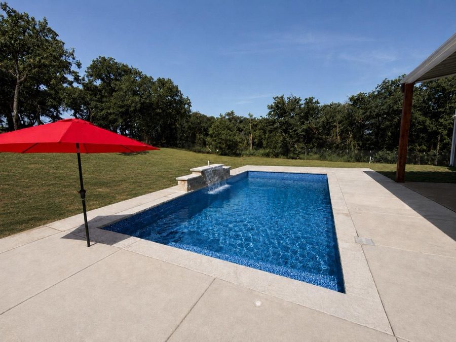 Vinyl inground pool with a red patio umbrella and covered outdoor living area